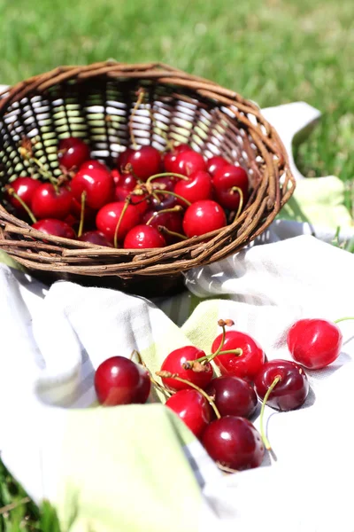 Doces cerejas maduras em cesta de vime, em fundo de grama verde — Fotografia de Stock