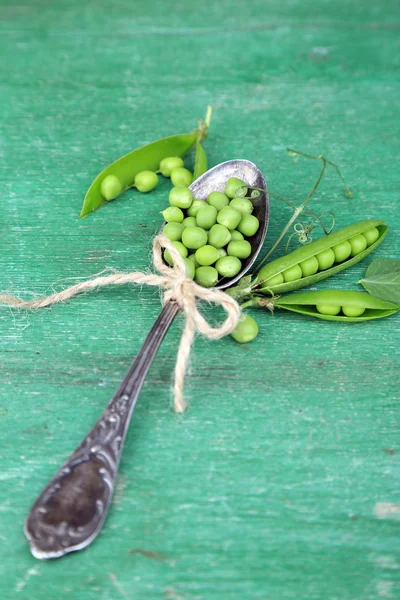 Pois verts frais dans une cuillère sur une table en bois — Photo