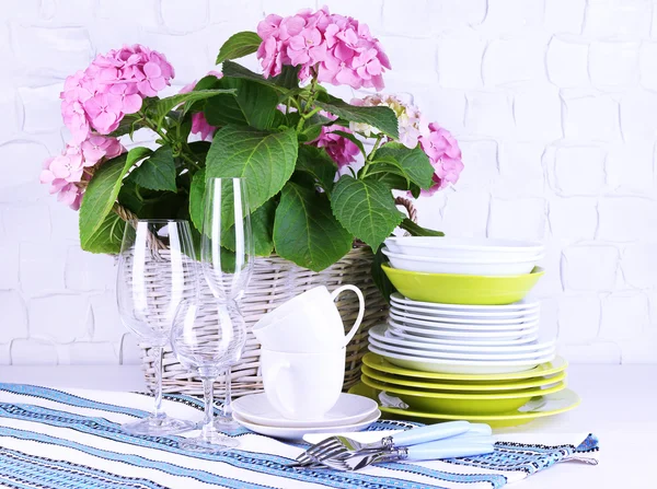Kvetoucí hortenzie a nádobí na stole na šedou stěnu pozadí — Stock fotografie