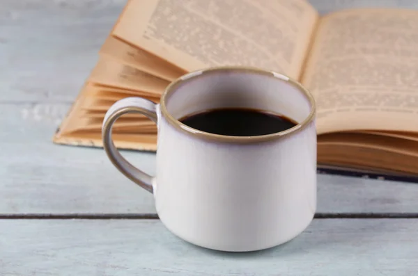 Copo com café quente e livro velho sobre fundo de madeira — Fotografia de Stock