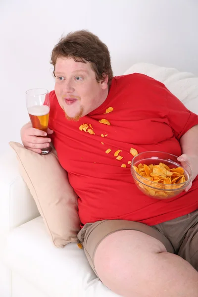 Lusta túlsúlyos férfi ül a kanapén, és nézi a televíziót — Stock Fotó
