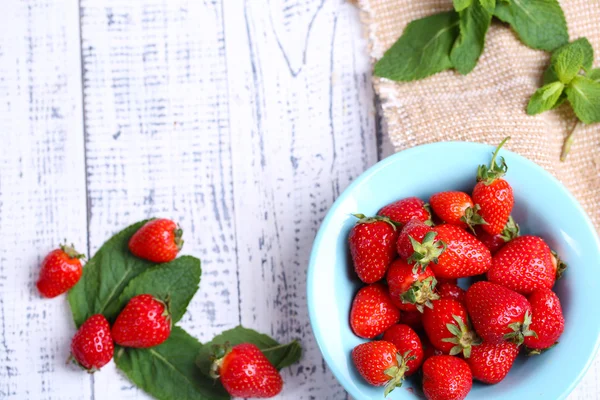 Fraises sucrées mûres dans un bol sur fond de bois de couleur — Photo