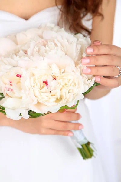 Bride holding wedding bouquet of white peonies, close-up, on light background — Stock Photo, Image