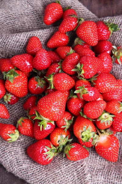 Ripe sweet strawberries on sackcloth napkin, on wooden  background — Stock Photo, Image