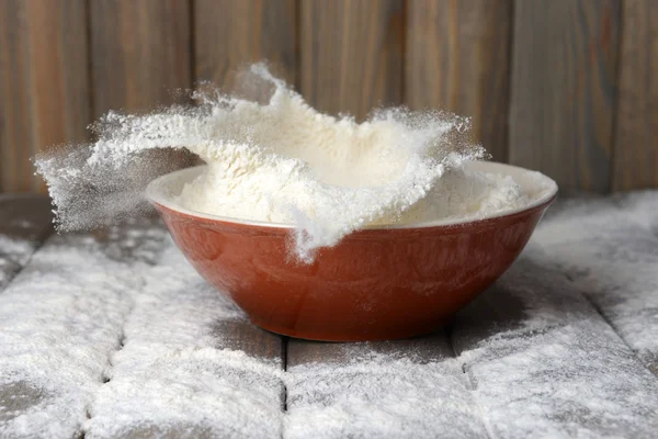 Farinha na tigela na mesa sobre fundo de madeira — Fotografia de Stock