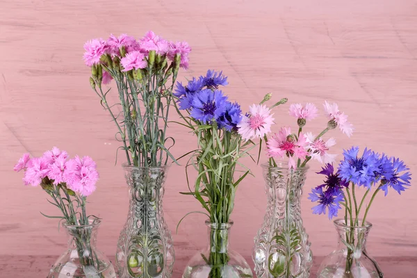 Hermosas flores de verano en jarrones sobre fondo de madera rosa —  Fotos de Stock