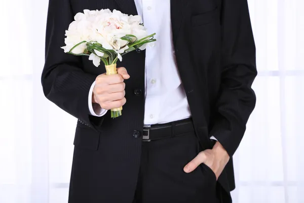 Uomo che tiene bouquet da sposa su sfondo chiaro — Foto Stock