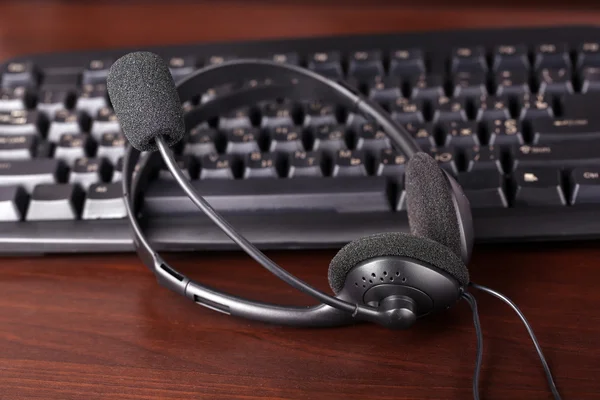 Headphone and keyboard close-up on wooden desk background — Stock Photo, Image