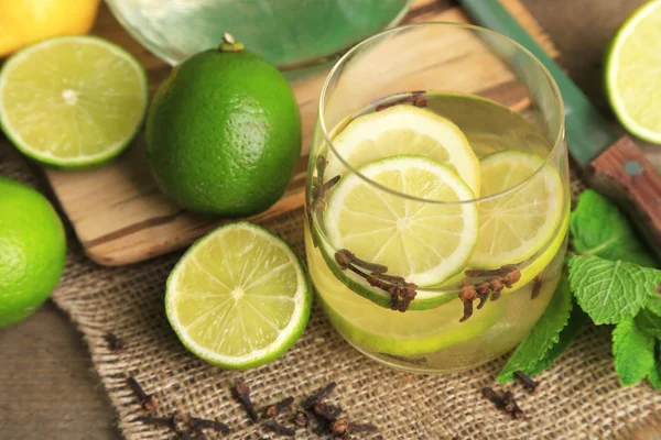 Fresh summer drink with lime and cloves in glass, on color wooden background — Stock Photo, Image