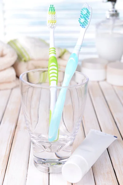 Cepillos de dientes en vidrio sobre mesa sobre fondo claro —  Fotos de Stock