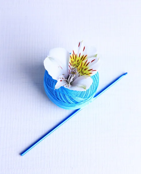 Colorful clew, crochet hook and fresh flower on light background — Stock Photo, Image