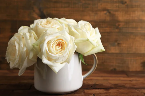 Krásné bílé růže v poháru na dřevěný stůl — Stock fotografie