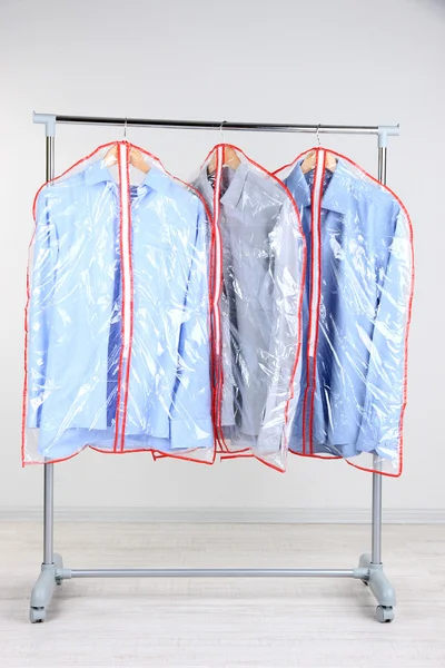 Office male clothes in cases for storing on hangers, on gray background — Stock Photo, Image