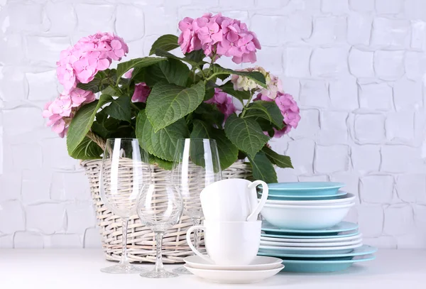 Цветущие гортензии и посуда на столе на сером фоне стены — стоковое фото