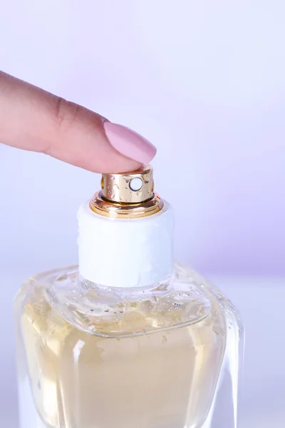 Garrafa de perfume na mão sobre fundo brilhante — Fotografia de Stock