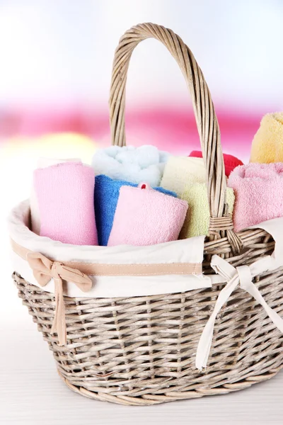 Colorful towels in basket, on table, on bright background — Stock Photo, Image