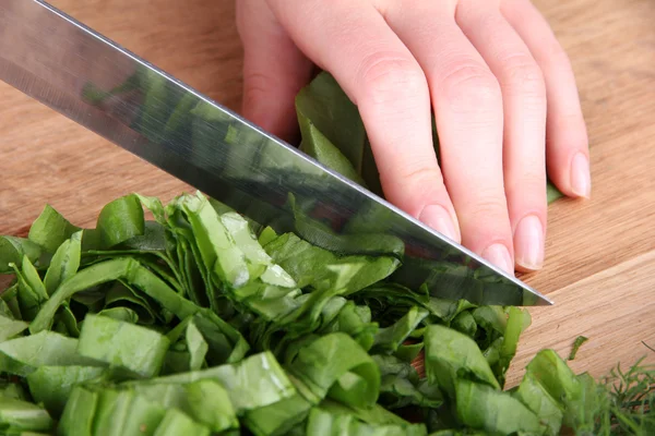 Female hand cutting greens on cutting board — Stock Photo, Image
