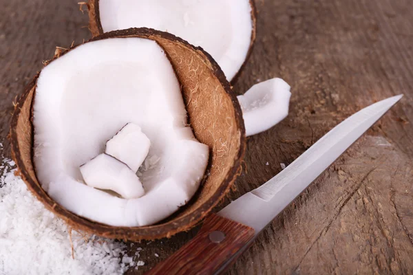 Сломанный кокос с ножом на деревянном фоне — стоковое фото