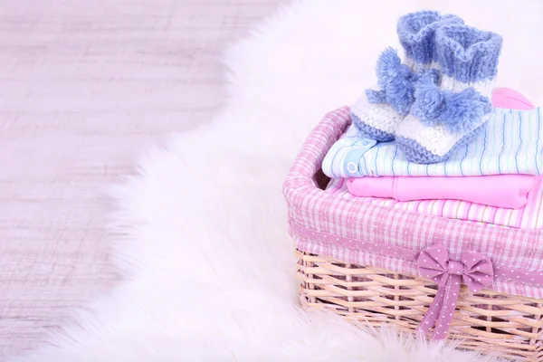 Baby clothes in basket on floor in room — Stock Photo, Image