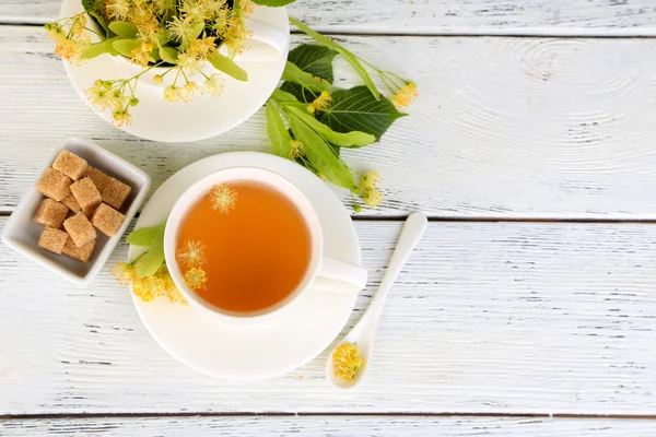 Sabroso té de hierbas con flores de tilo en la mesa de madera — Foto de Stock