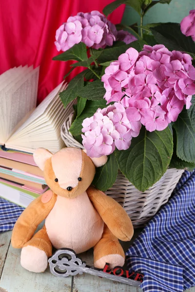 Hydrangea in basket with teddy bear and books close-up — Stock Photo, Image