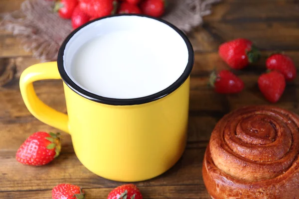 Mogna söta jordgubbar, färska bullar och mugg med mjölk på färg trä bakgrund — Stockfoto