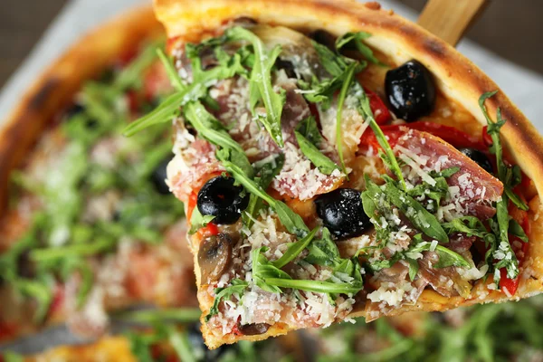 Pedaço de pizza com arugula em espátula de madeira, close-up — Fotografia de Stock