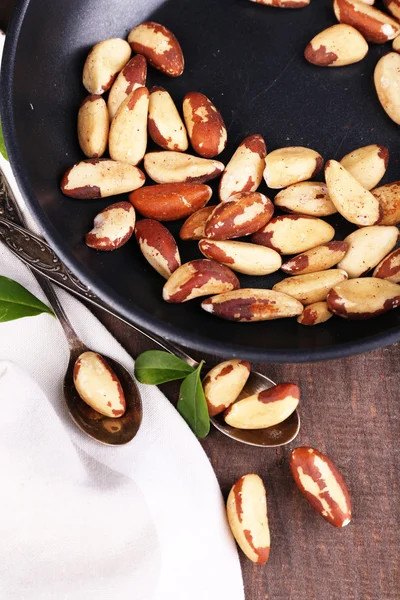 Tasty brasil nuts in pan on wooden background — Stock Photo, Image