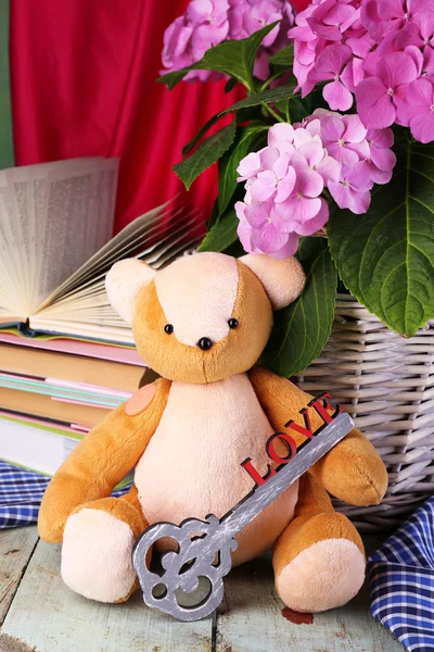 Hydrangea in basket with teddy bear and books close-up — Stock Photo, Image