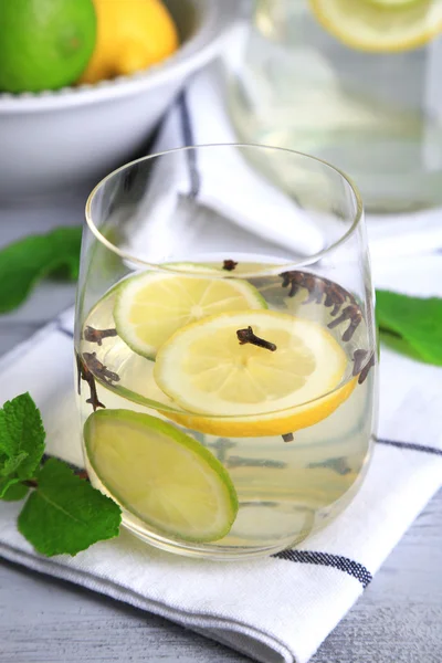 Boisson fraîche d'été à la chaux et clous de girofle en verre et cruche, sur fond de bois couleur — Photo