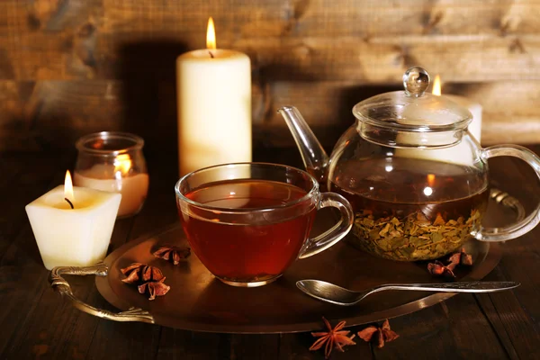 Composition avec thé en tasse et théière et bougies sur table, sur fond bois — Photo