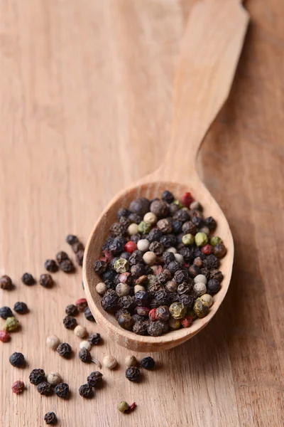 Pimienta de especias en cuchara sobre fondo de madera — Foto de Stock