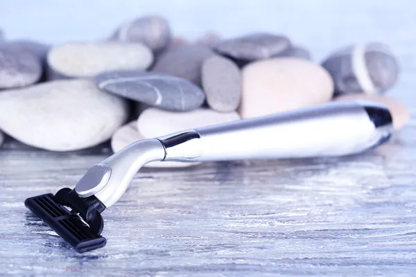 Shaving razor on stones on bright background — Stock Photo, Image