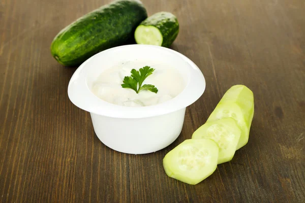 Cucumber yogurt in glass bowl, on color napkin, on wooden background — Stock Photo, Image