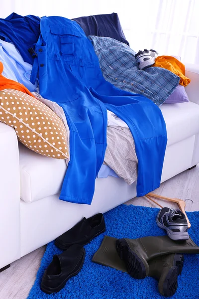 Ropa masculina desordenada y colorida en un sofá sobre fondo claro —  Fotos de Stock