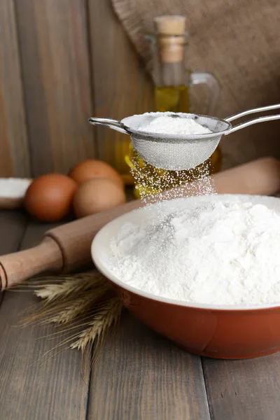 Mehl in Schüssel auf Tisch auf Holzgrund sieben — Stockfoto