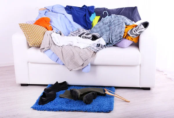 Roupas masculinas coloridas bagunçadas no sofá no fundo claro — Fotografia de Stock