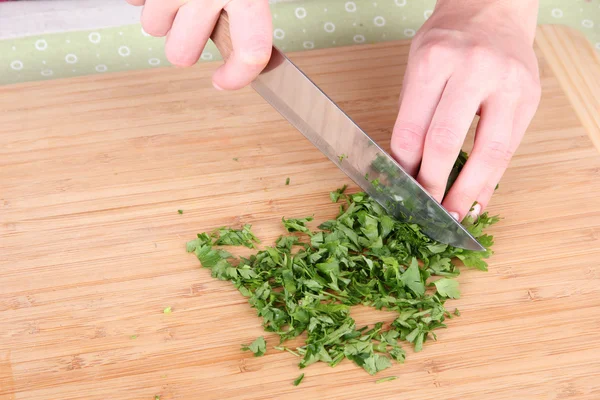 Weibliche Hand schneidet Grünzeug auf Schneidebrett — Stockfoto