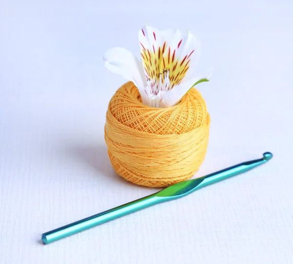 Colorful clew, crochet hook and fresh flower on light background — Stock Photo, Image