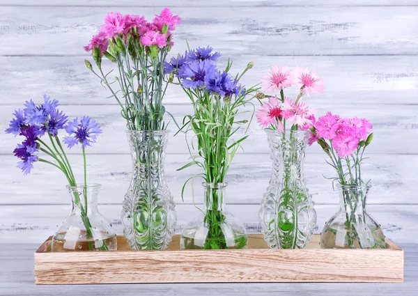 Schöne Sommerblumen in Vasen auf grauem Holzgrund — Stockfoto