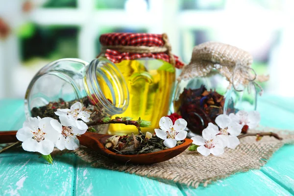 Assortiment van kruiden en thee en honing in glazen potten op houten tafel, op lichte achtergrond — Stockfoto