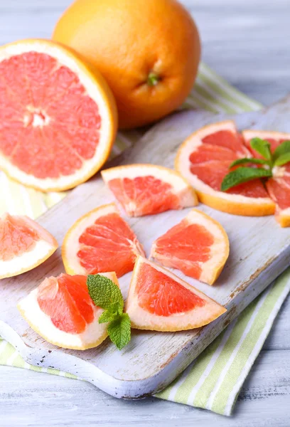 Mogen grapefrukt på skärbräda, på träbord, på ljus bakgrund — Stockfoto