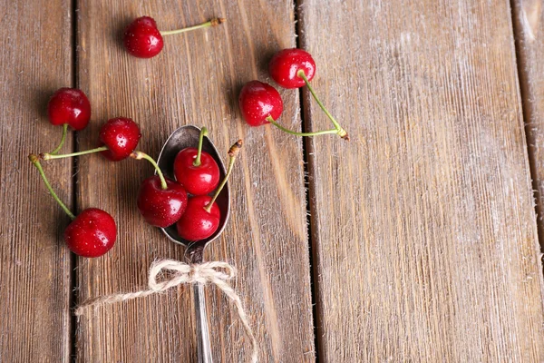 Reife Süßkirschen im Löffel auf Holztisch — Stockfoto