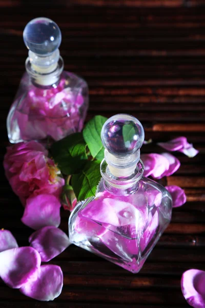 Olio di rosa in bottiglie su sfondo tappetino di bambù — Foto Stock