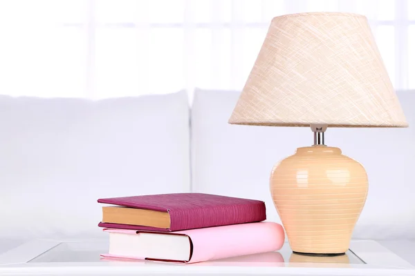 Books and lamp on coffee table in room — Stock Photo, Image