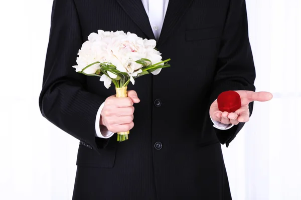 Man holding wedding bouquet and ring on light background — Stock Photo, Image