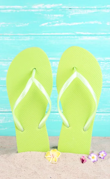 Bright flip-flops on sand, on wooden background — Stock Photo, Image