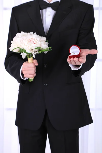 Man met bruiloft boeket en ring op lichte achtergrond — Stockfoto