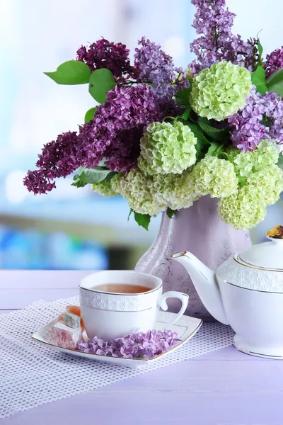 Composizione con teiera, tazza e bellissimi fiori primaverili in vaso, su tavolo di legno, su sfondo luminoso — Foto Stock