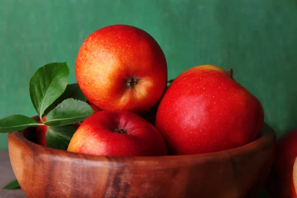 成熟的甜苹果，叶在木制背景的碗中 — 图库照片
